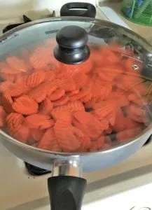Covered carrots cooking in a skillet
