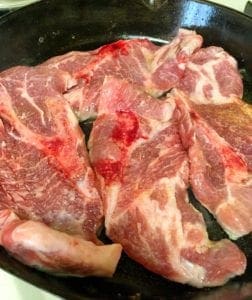 pork steaks frying in a pan