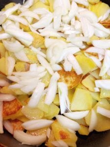 Adding sliced onions to the potatoes