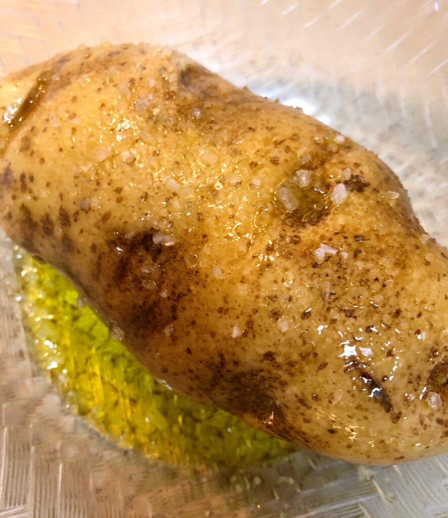 Olive Oil Being Applied to the Russet Potato in a Bowl