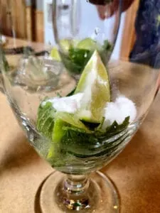 Adding Sugar Mint and Limes to Glass